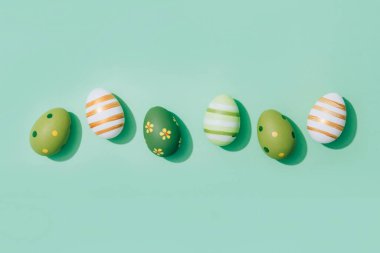 Easter greeting card - Easter eggs on pastel mint background with copy space. Flat lay. Selective focus. Central composition