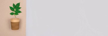 Banner - fincan olsun diye çevre dostu kahvenin maketi, üzerinde yeşil yapraklar olan açık gri arka planda fotokopi alanı olan kraft kağıt bardaklar. Sürdürülebilir ambalaj ve sıfır atık kavramı, seçici odaklanma