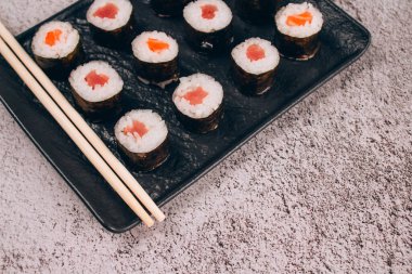 Klasik somon ya da ton balıklı sashimi, soya sosu ve soya çubuğu ile beton masa arkasında - maki sushi roll, nori maki. İnternetten sipariş edilen yemek konsepti, suşi barı menüsü. Paket yemek.