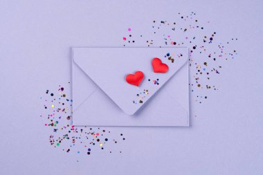2022 yılının modaya uygun renginde sevgililer günü festivali geçmişi. Mor zarfta kırmızı kalpler ve menekşe arkaplanda fotokopi alanı olan konfeti var. Düz yerde, üst tarafta. Tebrik kartı
