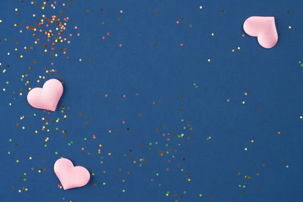 Fondo festivo con corazones rosados y pequeños destellos holográficos multicolores sobre fondo azul oscuro con espacio para copiar. Antecedentes de San Valentín para su proyecto —  Fotos de Stock