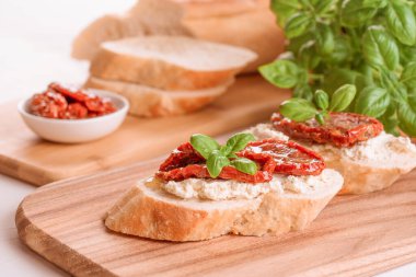 Klasik italyan aperatifi - bruschetas ya da ricotta peynirli tost ve ahşap masa arkasında fesleğenle kaplanmış güneşte kurutulmuş domates. Lezzetli aperatif