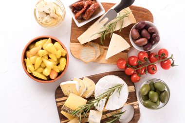 Peynir seçimi zeytin, bebek ve kurutulmuş domates, salamura bebek biberi, enginar ve beyaz masa arkasında kraker ile servis edilir. Aperatif için peynir tabağı - peynir, parmesan peyniri, camembert peyniri. Üst görünüm