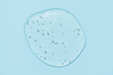 Mavi arka planda şeffaf kozmetik desenli baloncuklu jel damlası. Uzayı kopyala Banyo jeli arka planı, seçici odak