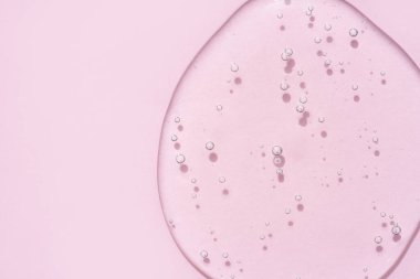 Şeffaf kozmetik desenli jel, pembe arka planda köpükler ve fotokopi alanı. Banyo jeli arkaplanı, üst görünüm