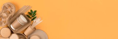 Çevre dostu sofra takımı olan pankart. Kraft kağıt kaplar, kağıt kaplar ve bardaklar, turuncu arka planda bambu çatal bıçak takımı, kopyalama alanı. Sokak yiyecekleri ambalaj konsepti. Etik tüketim, düz yatış, model.