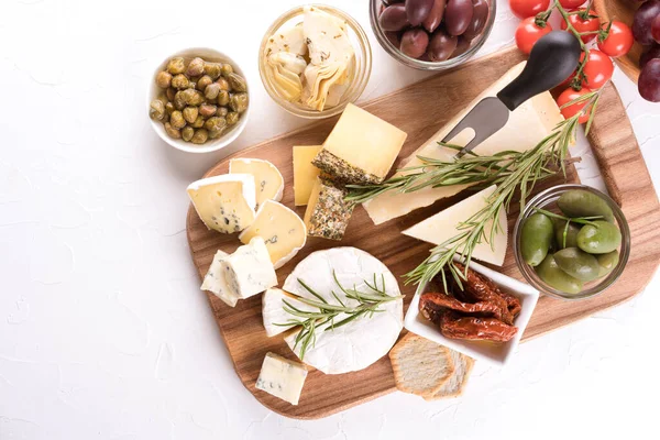 Peynir dilimli şarküteri tahtası ve geleneksel İtalyan antipastası çeşitleri. Kopyalama alanı olan beyaz masadaki peynir tabağı, seçici odak