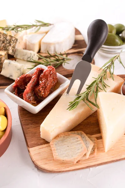 Katı ve olgunlaşmış peynirler. Peynir dilimli şarküteri tahtası ve geleneksel İtalyan antipastası çeşitleri. Beyaz masadaki peynir tabağı, dikey resim