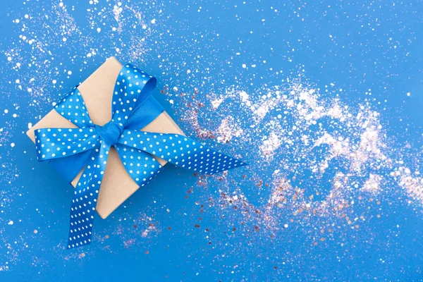 青いリボンがついたクリスマスプレゼントの箱は 周りに輝く青い背景に弓 コピースペース付きの美しいクリスマスと新年のお祝いの背景 ギフトボックス — ストック写真