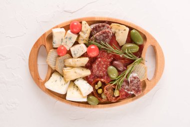 Peynir ve meze tabağında en iyi manzara. Geleneksel İtalyan panosu çeşitli peynirler, güneşte kurutulmuş domatesler, beyaz masada zeytin ve otlarla servis edilen sosisler - parmesan, dorblu, prosciutto, salam