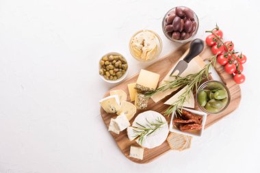 Çeşitli antipastel peynirlerle servis ediliyor. Zeytin, bebek ve güneşte kurutulmuş domates, enginar turşusu, kapari ve kraker beyaz masa üzerinde fotokopi alanı ile servis ediliyor. Aperatif için peynir tabağı - Brie, parmesan, camembert, dorblue