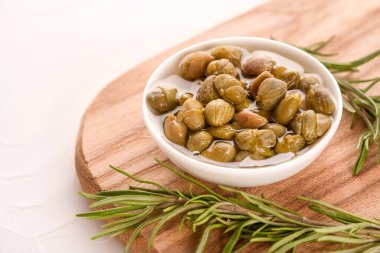 Tahta kesme tahtasında biberiyeyle servis edilen turşu turşulu beyaz kase, kopyalama alanı olan beyaz masa arka planı - geleneksel İtalyan antipastası