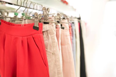 Askılarda farklı kıyafetler. Moda mağazasında yeni moda koleksiyonu. Kıyafet kiralama ya da satış konsepti. Giysiler kopya alanı ile bulanık depolama arka planına karşı dururlar
