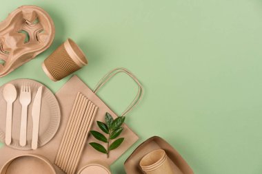 Sürdürülebilir gıda ambalajı kavramı - Kraft kağıt yemek bardakları, kaplar, kağıt torbalar, ahşap bambu çatal bıçak seti ve fotokopi alanı olan açık yeşil arka planda pipet içmek. Sokak yemekleri kağıt çatal bıçakları götürür.