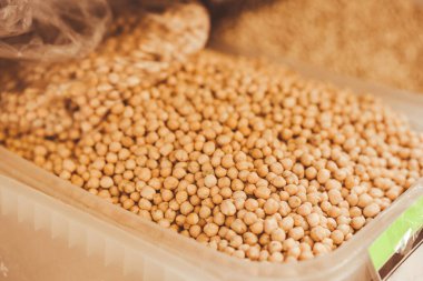 Arka planda fotokopi alanı olan plastik kabın içinde kurumuş çiğ nohut. Küresel gıda krizi konsepti