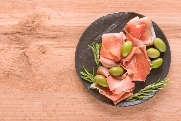 Portakallı şarküteri tabağı, zeytinli, ahşap masa zemininde fotokopi alanı ile servis ediliyor. Geleneksel İtalyan antipastası ile siyah tabak. Seçici odak
