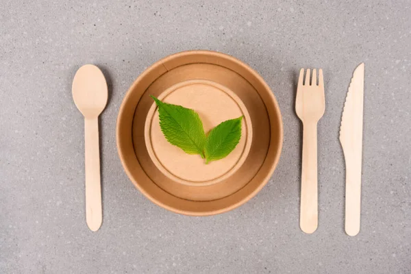 Kağıt çatal bıçak takımı, eko sofra takımı kağıt tabak, yiyecek kabı ve gri beton zemin üzerine kurulmuş ahşap bambu çatal bıçak takımı. Sürdürülebilir gıda paketleme kavramı