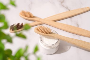 Doğal bambu diş fırçaları ve mineral diş tozu beyaz masa arkasında şeffaf kaplarda kaolin. Doğal banyo ürünleri, organik diş fırçası. Model görüntüsü. Üst görünüm