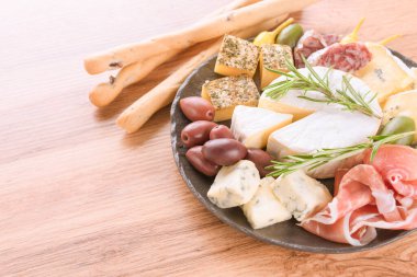 İtalyan antipasti tabağı. Peynir, prosciutto, zeytin, otlar ve fotokopi alanı olan ahşap masa arkasında Grissini ekmekleriyle servis edilen salamlı şarküteri tabağı. Mutlu saat menüsü