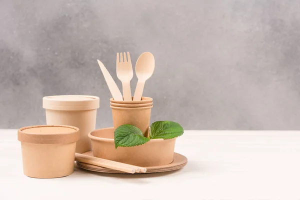 stock image Catering, paper utensils - paper plates, food containers, cups and wooden cutlery set against gray wall background with copy space. Sustainable food packaging concept