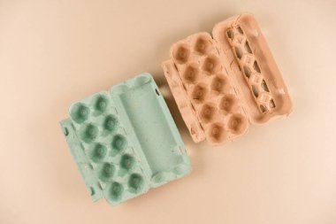 Hamur hamurundan yapılmış yumurta kutuları ve açık kahverengi arka planda doğal saman. Çevre dostu geri dönüşümlü yumurta kutuları, sürdürülebilir gıda paketleme konsepti. Düz yat, model al.