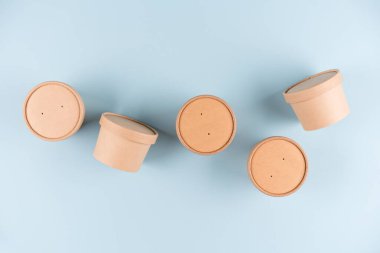 Çorba için eko Kraft kağıt yiyecek kapları ya da dondurma, açık mavi arka planda kağıt kapaklı bardak, model resim. Sürdürülebilir gıda paketleme konsepti. Düzleştirme biçimi