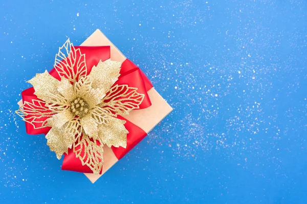 赤いリボン弓と周りの輝きとコピースペースと青の背景に伝統的な装飾的なクリスマスの花のポインセチアと美しいクリスマスプレゼントボックス お正月ギフトボックスのコンセプト — ストック写真