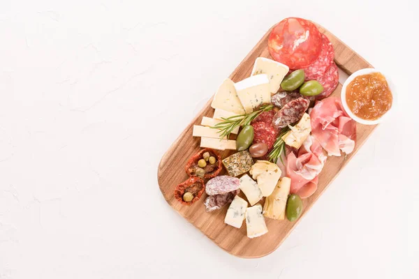 İtalyan panosu çeşitli peynirler, güneşte kurutulmuş domates, zeytin, reçel ve otlarla servis edilen sosisler beyaz masada - parmesan, dorblu, prosciutto, salam. Peynir ve meze tabağı. Boşluğu kopyala