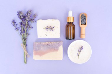 Doğal bitkisel kişisel bakım ürünleri - kozmetik lavanta yağı ya da yüz serumu, banyo tuzu, el yapımı sabun ve şampuan çubukları mor arka planda. Lavanta özlü doğal bitkisel kozmetik