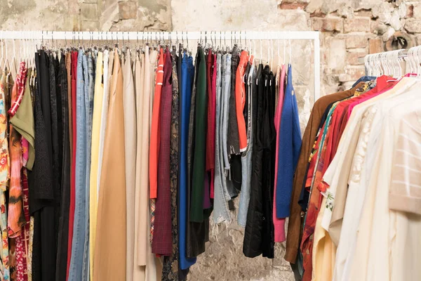 Multicolor clothes on hangers - second hand clothes store or thrift shop. Clothing rental service. Clothes rail with copy space for text. Selective focus. Sustainable fashion concept