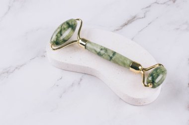 Beyaz mermer masa üzerinde yüz masajı için yeşim yüzlü gua sha. Doğal taşlardan yapılan yüz masajı aletleri. Cilt bakım aletleri. Seçici odak