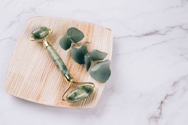 Yüz masajı paketi. Yeşim yüzlü gua sha beyaz mermer masa üzerinde. Doğal taşlardan yapılan yüz masajı aletleri. Cilt bakım aletleri. Seçici odak