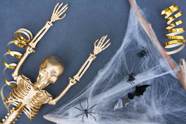 Halloween background. Golden skeleton, cobweb, bats and spiders over dark gray background. Halloween celebration concept. Minimal style