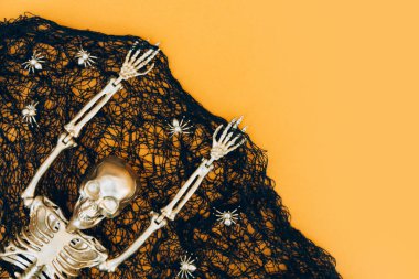 Cadılar Bayramı arkaplanı siyah örümcek ağları, altın örümcekler ve turuncu arka plan üzerinde altın iskelet ve Cadılar Bayramı projeniz için fotokopi alanı. Davet şablonu