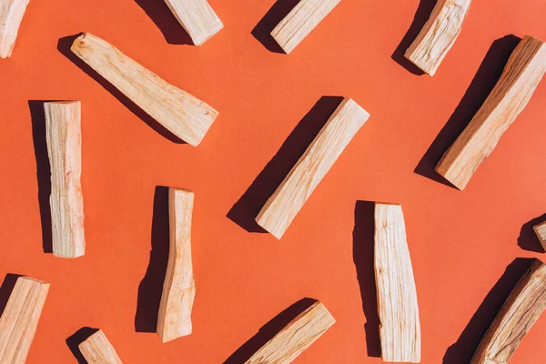 Flat lay composition with palo santo sticks over orange red background with shadows. Holy wood sticks for meditation and spiritual practices. Room fumigation ritual. Selective focus