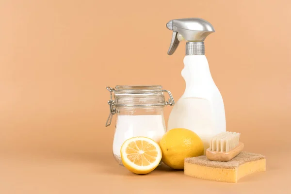 Green household. Natural homemade cleaners - baking soda, lemon, citric acid, spray bottle against light brown background with copy space. Bio organic detergent products