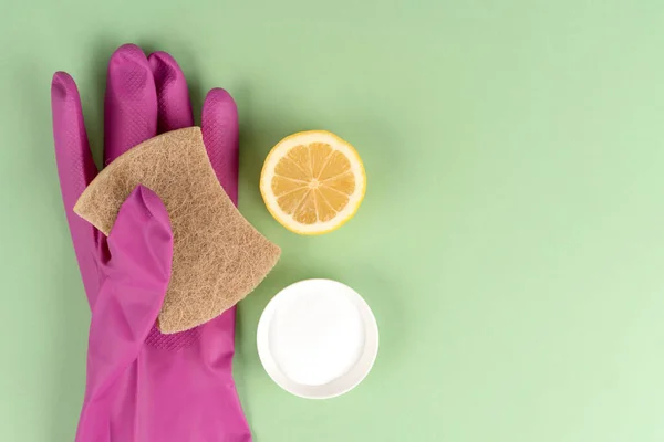 Natural household cleaners - eco sponge with baking soda or citric acid and lemon over green background with copy space. Homemade improvised cleaning products, green household concept