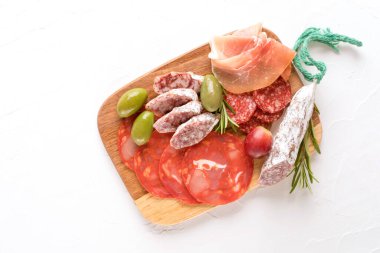 Farklı türde sosislerle servis edilen şarküteri tabağı. Salam, bresaola, beyaz masada zeytinli proscuitto. Kopyalama alanı olan pankart menüsü arkaplanı. Geleneksel İtalyan yemekleri - antipasti