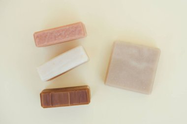 Doğal bitkisel malzemelerle yapılmış organik sabun ve açık sarı zemin üzerinde gerekli yağlar. Evde vegan cilt bakımı ürünleri ve kozmetik ürünleri yapıyorum. Model resmi