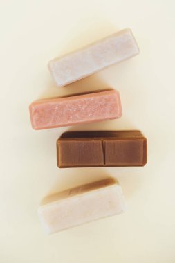 Açık sarı arka planda doğal bitkisel malzemelerle yapılmış sabunlar. Evde vegan cilt bakımı ürünleri ve kozmetik ürünleri yapıyorum. Düz yatış stili, dikey görüntü. Yukarıdan görüntüle