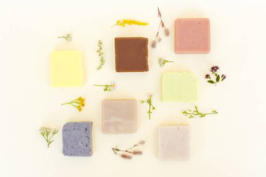 Doğal bitkisel malzemelerden, otlardan ve çiçeklerden yapılmış el yapımı vejetaryen sabunu açık sarı arka planda. Evde cilt bakımı ürünleri yapıyorum. Düzleştirme biçimi 