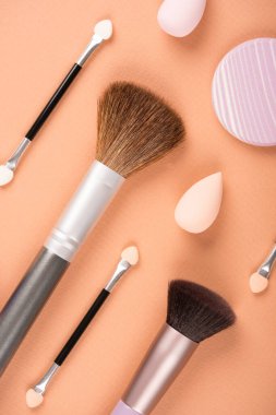 Makyaj ve güzellik konsepti. Pastel bej arka planda farklı makyaj fırçaları, süngerler ve aplikatörler var. Düz konum biçimi, dikey resim