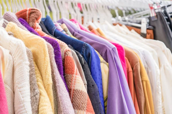 Clothes on hangers - second hand clothes store or thrift shopping concept. Clothing rental service. Clothes rail with copy space for text. Selective focus