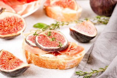 Çiğ incir, krem peynir, prosciutto, ceviz ve otlu beyaz masa. Hızlı, sağlıklı bir kahvaltı fikri. İtalyan mutfağı. Seçici odak