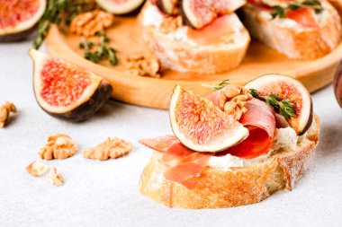 İncirli, krem peynirli, jambonlu, cevizli ve kekikli bruschetta 'nın yakın görüntüsü. Hızlı, sağlıklı bir kahvaltı fikri. İtalyan mutfağı. Seçici odak