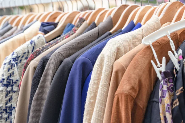 Clothes on hangers - second hand clothes store or thrift shopping concept. Clothing rental service. Vintage jackets for sale at flea market. Selective focus