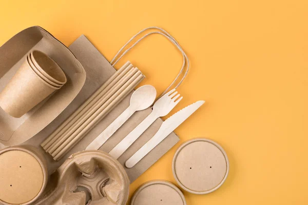 Street food paper packaging, recyclable utensils, zero waste packaging. Eco-friendly tableware bundle over orange background with copy space - sustainable paper food packaging. Flat lay