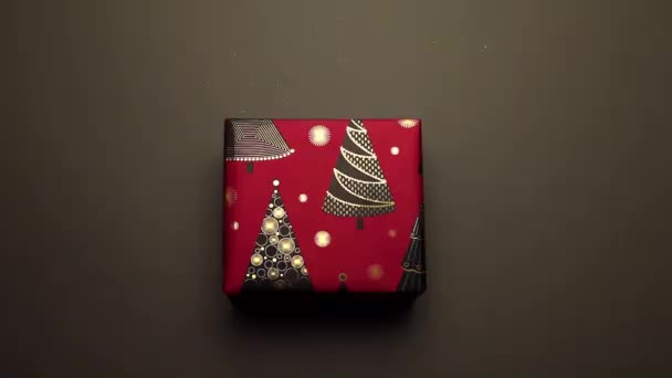 Pakowanie prezentów noworocznych. Żółta wstążka na czarnym tle. Prezent z choinkami. — Wideo stockowe