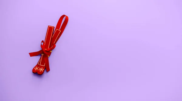 Um brinquedo para uma árvore de Natal. Esquis vermelhos em um fundo de cor pantone. Um presente de férias. Fotos De Bancos De Imagens