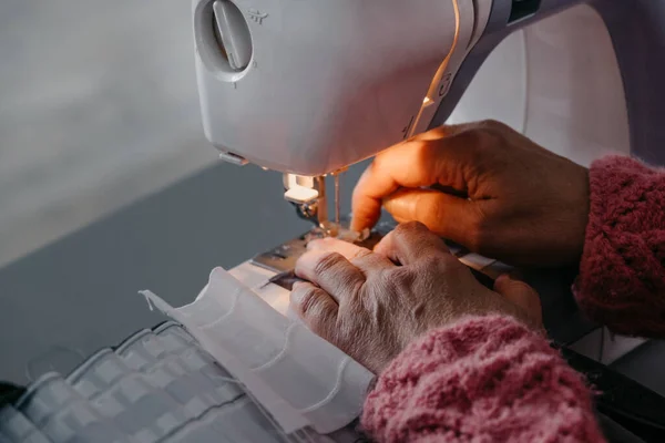 Close-up. As mãos de uma mulher adulta estão costurando em uma máquina de costura. Fabricação de vestuário de uso. Fotos De Bancos De Imagens Sem Royalties